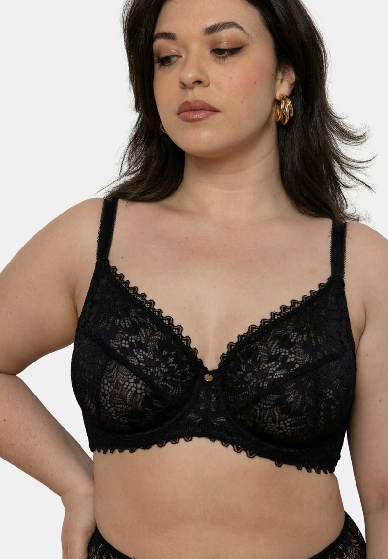 Soutien-gorge en dentelle noire avec des bords festonnés, motif floral, soutien-gorge à armatures et bretelles ajustables. Petit accent doré au centre.