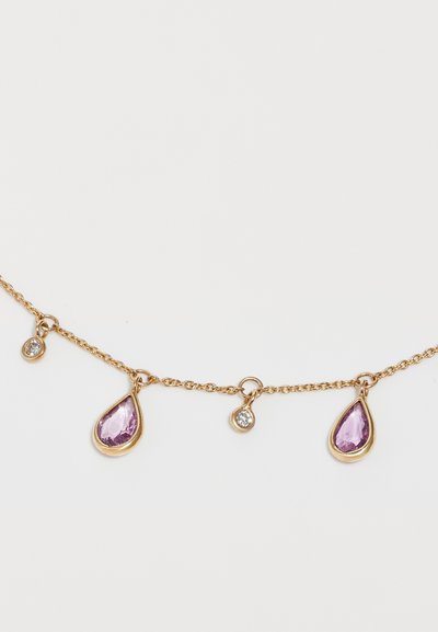 Zelta ķēdes kaklarota, kurā ir divi asarveida purpura dārgakmeņi un divi mazi apļveida caurspīdīgi akmeņi, kas izceļ delikātu dizainu un tekstūru.