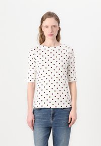 Haut blanc à manches courtes avec des pois multicolores en bordeaux et marron. Texture lisse, encolure arrondie, design ajusté.