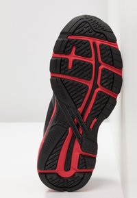 Černá a červená sportovní podešev, která je opatřena texturovanou gumou pro lepší přilnavost, s cik-cak vzorem, drážkami a výrazným logem Asics.