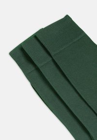 Grüne gerippte Socken mit strukturiertem Strick und breiten, verstärkten Bündchen für Komfort und Haltbarkeit. Zwei Paar werden angezeigt, die sich leicht überlappen.
