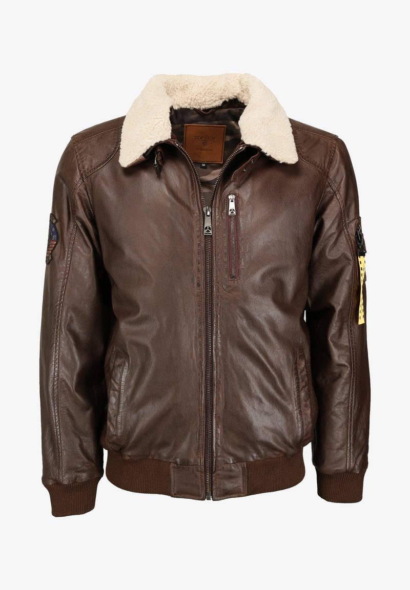 Brun læder bomberjakke med krave af kunstpels, ribbede ærmer og talje. Har flere lynlåslommer og et mærke på ærmet.