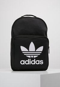 Black backpack made of durable fabric, featuring a large white Adidas logo on the front pocket and a rounded top with a top handle.