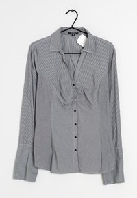 Chemise boutonnée à rayures noires et blanches, dotée d'un col, de manches longues et d'un détail froncé à l'avant.
