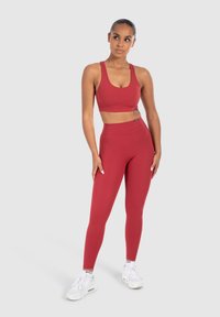Rode sportieve crop top en high-waisted legging van rekbare stof. Bevat een gladde textuur en minimale hardware.
