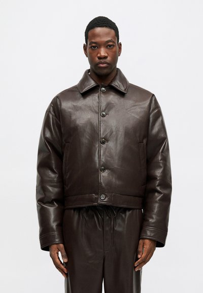 Jachetă din piele maro, scurtă, cu închidere prin butoane în față, guler mare și buzunare laterale. Textură fină cu o strălucire subtilă.