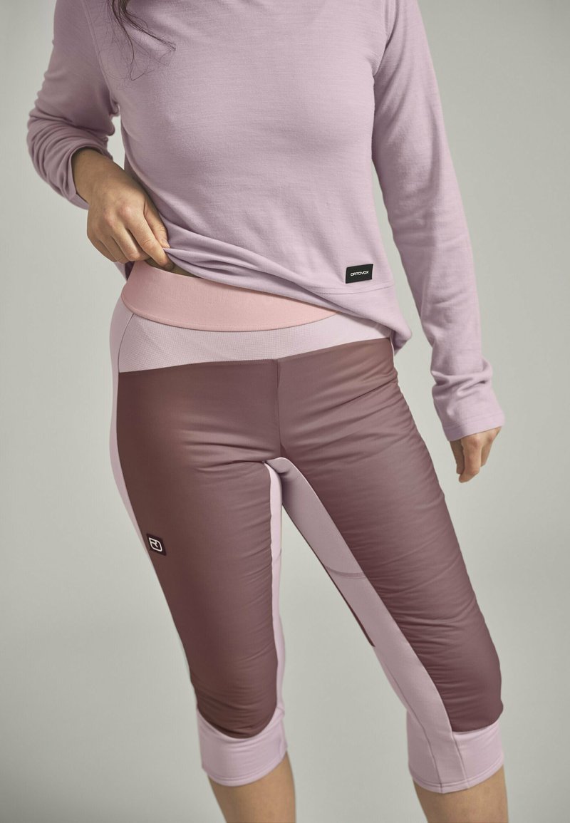 Light purple long-sleeve top paired with fitted, three-quarter length leggings featuring a gradient of pink and brown shades and a waistband detail.