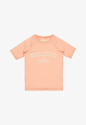 Brzoskwiniowa koszulka z krótkim rękawem Billabong typu rash guard z białym napisem "BILLABONG SINCE 1973" i logo fali na przodzie, z okrągłym dekoltem.