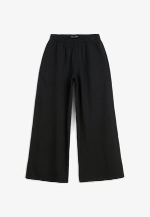 Czarne szerokie spodnie z elastycznym pasem i kieszeniami po bokach, zaprojektowane dla luźnego i wygodnego noszenia.