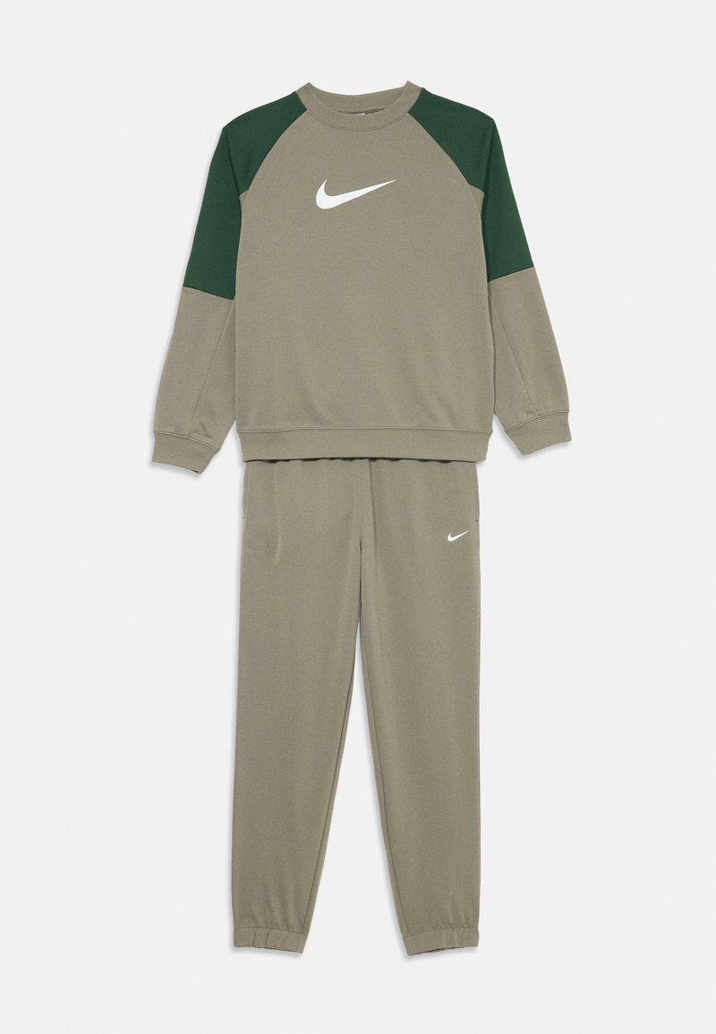 Olīvzaļš Nike sporta tērps ar tumši zaļiem plecu paneļiem džemperī un baltām Nike logo uz krūtīm un biksēm.