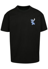 Black cotton t-shirt featuring a small blue cartoon character print on the upper left side. Short sleeves and round neckline.