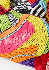 Tissu perlé présentant des couleurs vibrantes telles que le rose, l'orange, le vert et le jaune, avec des formes circulaires et cylindriques créant une texture en couches.