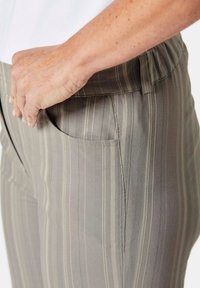Grijze gestreepte broek met een zachte textuur, voorzien van een elastische tailleband en zijzakken. De strepen zijn lichtgrijs en gebroken wit.