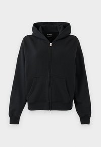 Crna zip-up dukserica od mekog materijala, s kenguruh džepom, podesivom kapuljačom s vezicom te rebrastim rukavima i donjim rubom.
