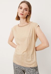 Beige top met korte mouwen, voorzien van een ronde halslijn en een zachte textuur, met een subtiele glans en zijsplijten voor extra detail.