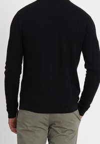 Černý pletený svetr s texturovaným vzorem, žebrovanými manžetami a lemem. Slim fit, dlouhé rukávy a kulatý výstřih.