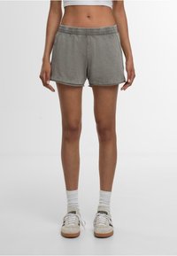 Shorts gris en coton avec une ceinture élastique, des coutures latérales et une coupe décontractée. Ils présentent une texture lisse et un ourlet légèrement arrondi.