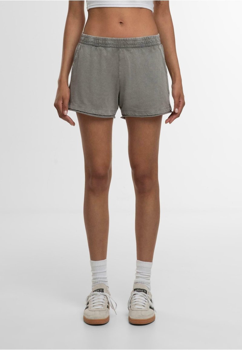Shorts gris en coton avec une ceinture élastique, des coutures latérales et une coupe décontractée. Ils présentent une texture lisse et un ourlet légèrement arrondi.