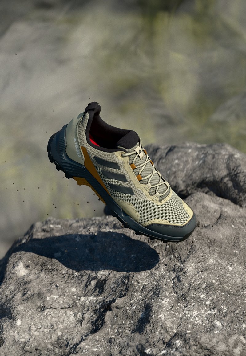 Chaussure de trail de course légère, beige, avec un dessus en mesh, des accents noirs, un capuchon de pied texturé et une semelle extérieure robuste pour une meilleure adhérence.