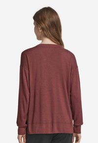 Mörkröd tröja med avslappnad passform, ribbade mudd och nederkant, lätt stickad textur och sänkta axelsömmar.