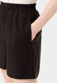 Černé šortky vyrobené z lehkého materiálu, s elastickým pasem, bočními kapsami a volným střihem s hladkým povrchem.