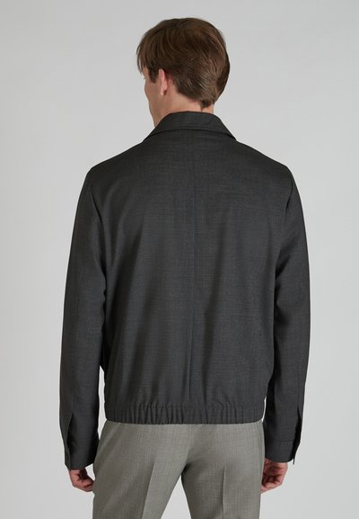 Veste gris foncé en tissu texturé, dotée d'un col, d'un ourlet élastique et de manches longues. La vue montre le détail du dos.