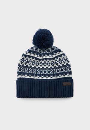 Navy blue and white knitted winter hat with geometric pattern, folded ribbed brim, large pom-pom on top, and small leather brand tag.