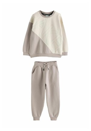 Light beige sweatshirt with a diagonal design and "BAKER" text, paired with matching elastic waist jogger pants in a similar tone.