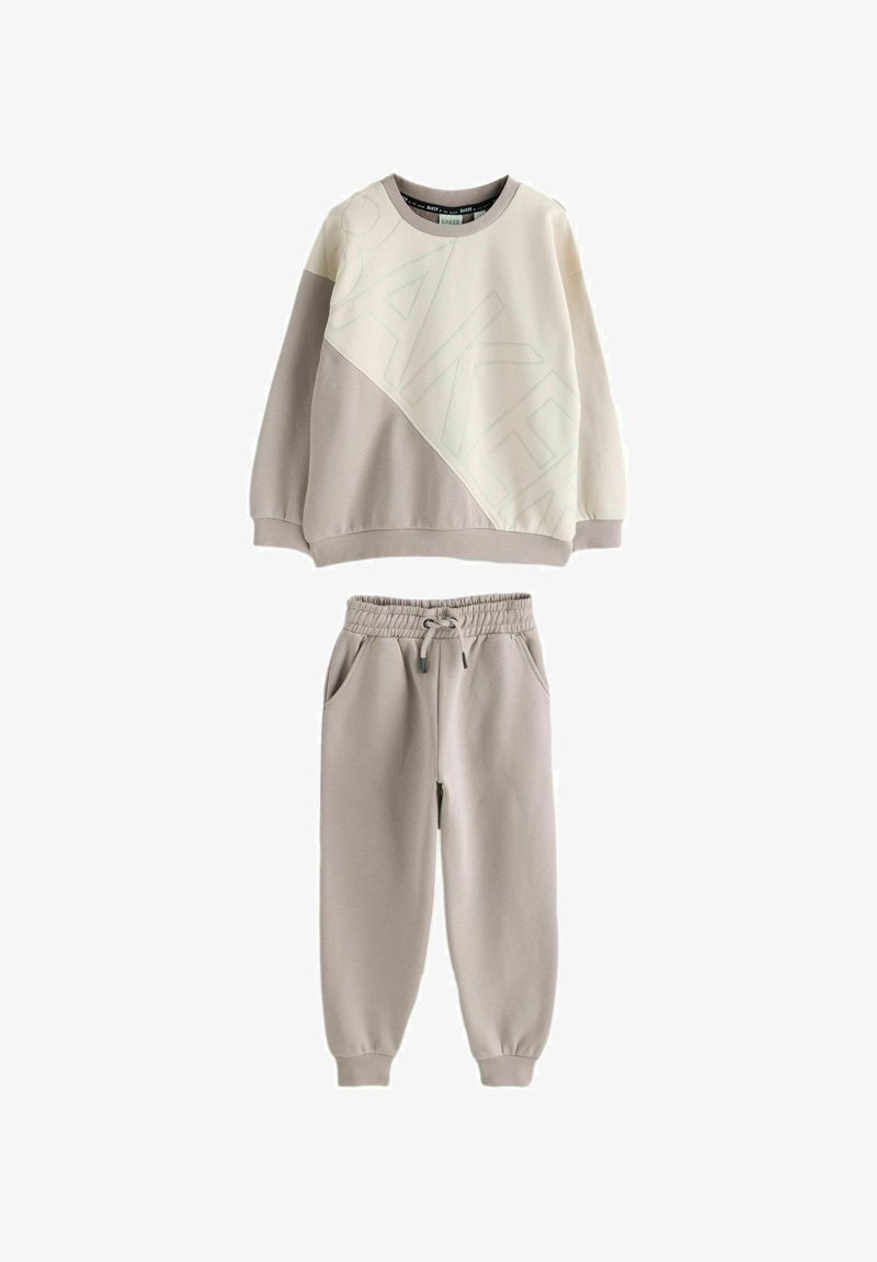 Hellbeiger Pullover mit diagonalem Design und dem Schriftzug "BAKER", kombiniert mit passenden Jogginghosen mit elastischem Bund in einem ähnlichen Farbton.