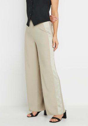 Pantalones de pierna ancha beige con una franja lateral de satén; textura suave; combinados con una blusa negra sin mangas y sandalias de tacón negras.