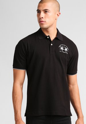 Polo nero in cotone, con colletto, maniche corte e un logo bianco ricamato sul petto. Accenti grigi sottili ai polsini.