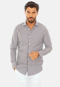 Camicia a righe con strisce verticali sottili marroni e bianche, maniche lunghe e colletto classico. Presenta una chiusura con bottoni frontale.