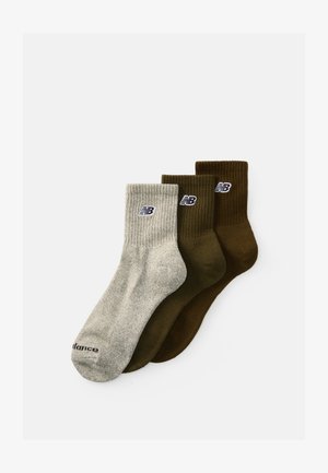 Trois paires de chaussettes montantes : une grise clair côtelée, deux solides vert foncé et marron, toutes avec un petit logo sur le revers.