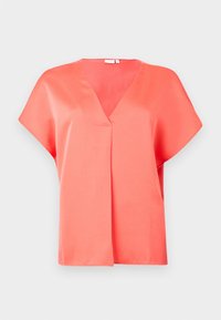 Blouse corail à manches courtes, col en V, coupe fluide, avec un subtil pli devant.