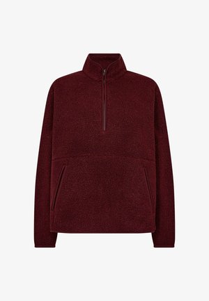 Bordo fliso megztinis su pusiau užtrauktuku ir šoninėmis kišenėmis, turintis tekstūruotą paviršių. Ypatingas laisvas kirpimas ir ilgomis rankovėmis.