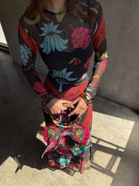 Langermet, gjennomsiktig kjole med blomsterprint i livlige farger. Tilbehørsveske med bambushåndtak og sløyfedetalj med matchende design.