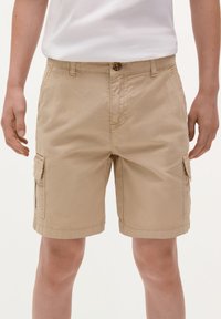 Pantaloni cargo beige con chiusura a bottone, dotati di tasche laterali e una vestibilità morbida. Realizzati in tessuto leggero con dettagli di cucitura in vista.