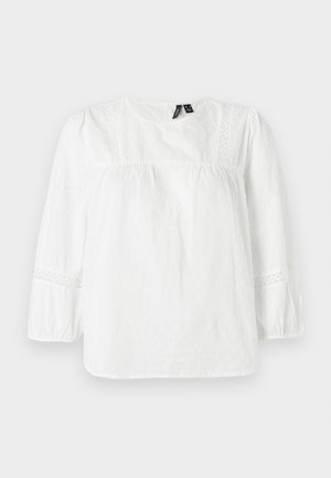 Blouse blanche à manches longues en coton texturé avec des manches bouffantes, des accents en dentelle le long des épaules et des poignets, et un col rond.