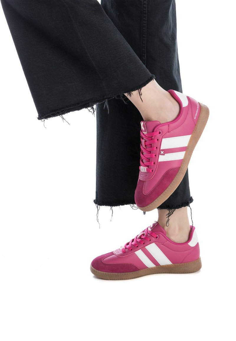Le sneakers atletiche rosa presentano un mix di materiali lisci e testurizzati, con strisce bianche e una suola in gomma beige. Il design include una punta rotonda e un davanti con lacci.