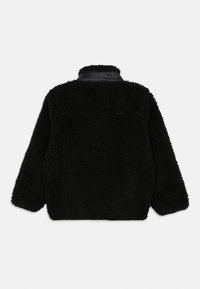 Giacca di fleece nera con tessuto testurizzato, maniche lunghe e colletto nero liscio, vista da dietro su uno sfondo bianco.