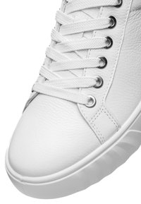 Witte leren sneaker van voren met witte, gestructureerde veters door metalen oogjes en dikke witte rubberen zool.
