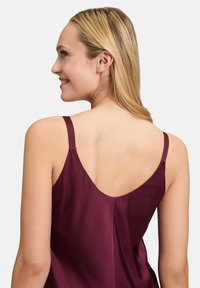 Burgunderfarbene Seiden-Camisole mit dünnen Trägern und ausgeprägt V-förmigem Rückendesign, mit glatter Textur und lässiger Passform.