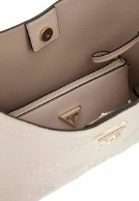 Interno di una borsa in pelle rosa chiaro con motivo impresso, dotato di una tasca con zip e un'etichetta a forma di triangolo, rifinita con un bordo scuro.