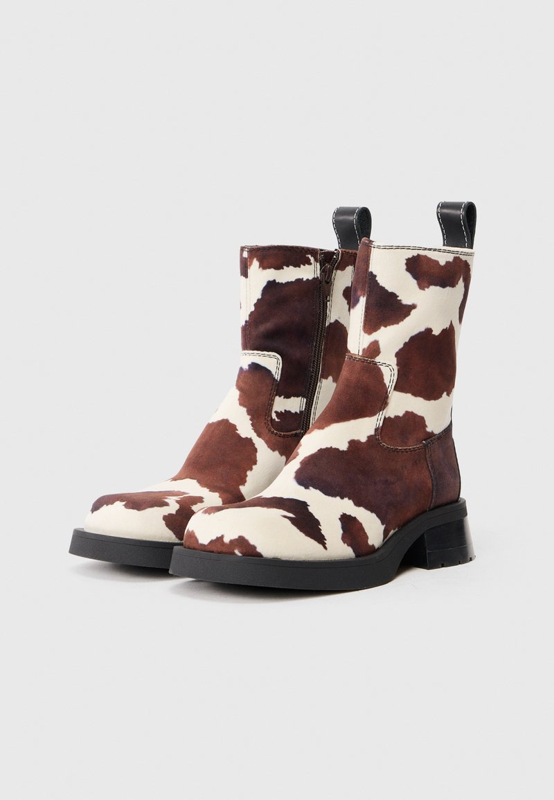 Cowhide-patterned ankle boots featuring a mix of brown and white hues, with a smooth texture, a rounded toe, and a low black heel.