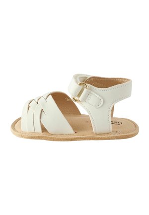 Sandale blanche pour bébé avec des brides avant tissées, une bride à la cheville avec une boucle dorée et une semelle souple couleur beige sur fond blanc.