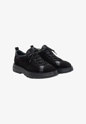 Zwarte suède lage sneakers met gestructureerde zwarte accenten, vetersluiting en een dikke rubberen zool met diepe profiel voor grip.