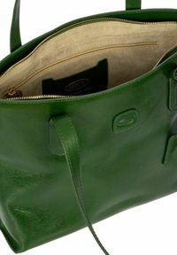 Sac à main en cuir vert avec une texture lisse, fermeture éclair et intérieur beige. Comprend des poches intérieures et une étiquette de logo. Deux poignées.