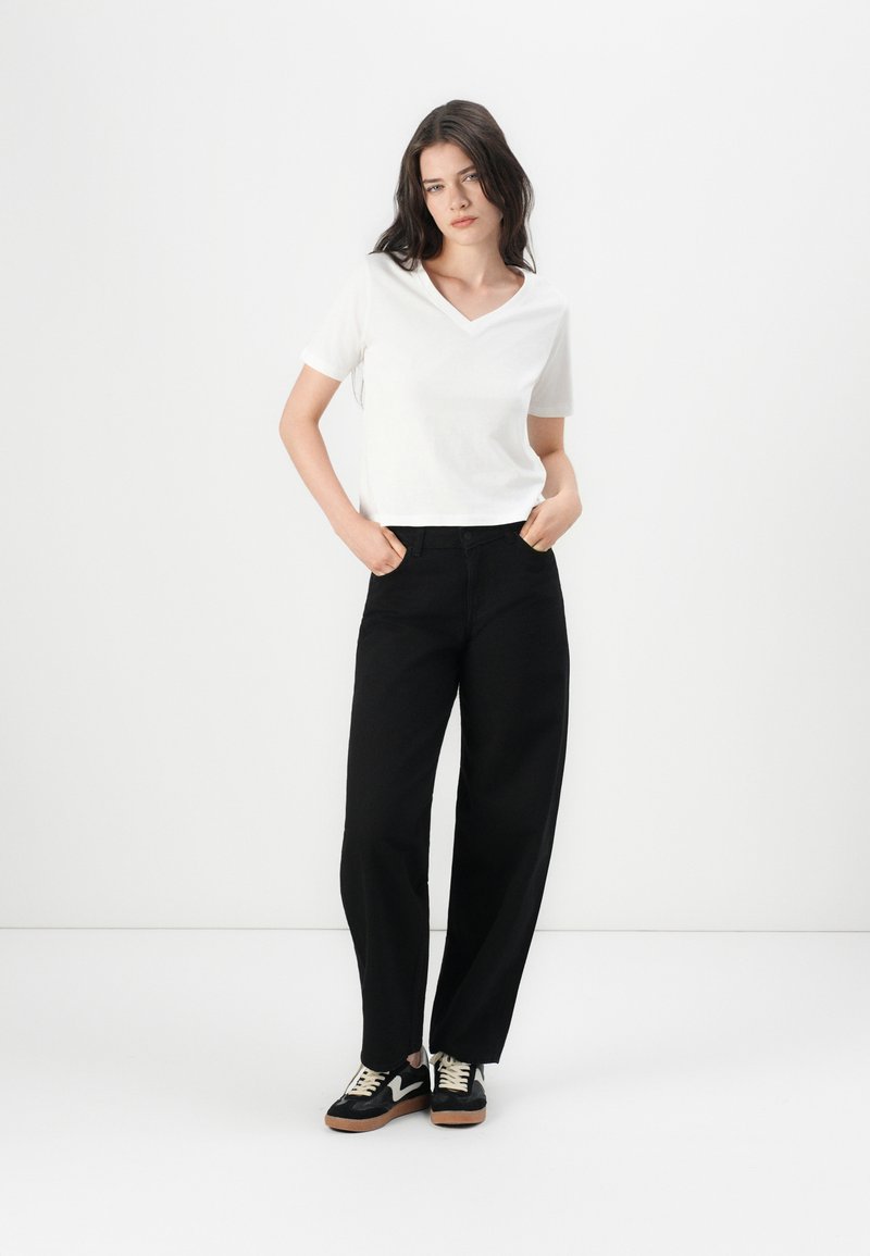 White V-neck t-shirt, black wide-leg trousers, and black sneakers with beige accents. Simple, contemporary design with a relaxed fit.