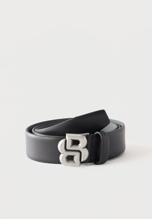 Ceinture en cuir noir enroulée avec une boucle métallique argentée présentant un design stylisé double "B" sur fond blanc.