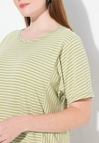 Camiseta a rayas verdes hecha de tela suave, con un escote amplio y mangas cortas. Rayas horizontales blancas en toda la prenda.
